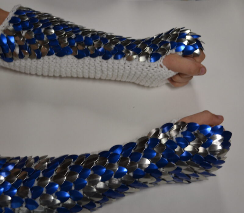 Long silver and blue knitted scalemaille gauntlets on white yarn