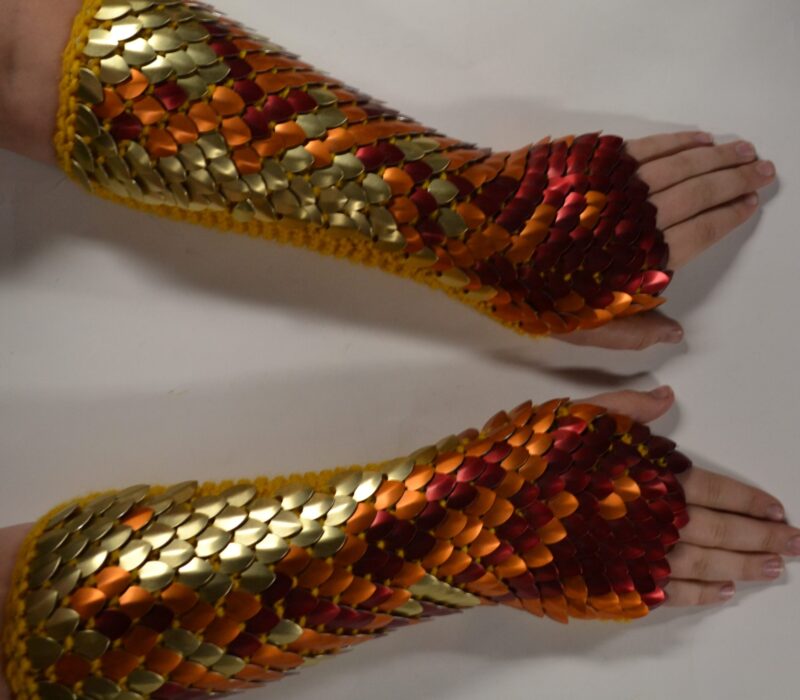 Long dragonhide scalemaille gauntlets in gold, orange, and red phoenix pattern on gold yarn.