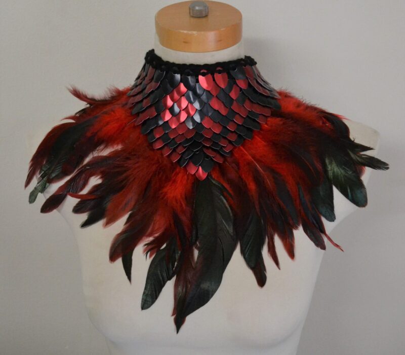 A black and red dragonhide collar with matching feather trim, modelled on a mannequin