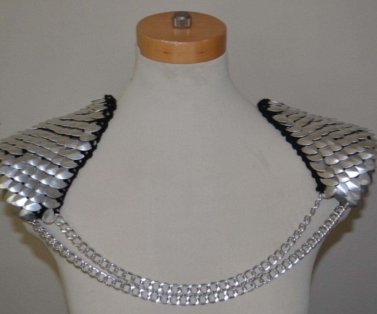Silver knitted scalemaille epaulets connected by double silver chains, modelled on a manequinn
