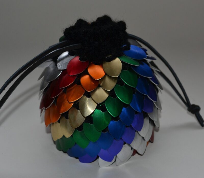 A large, rainbow-striped scalemaille dicebag, cinched shut with black leather cord. 