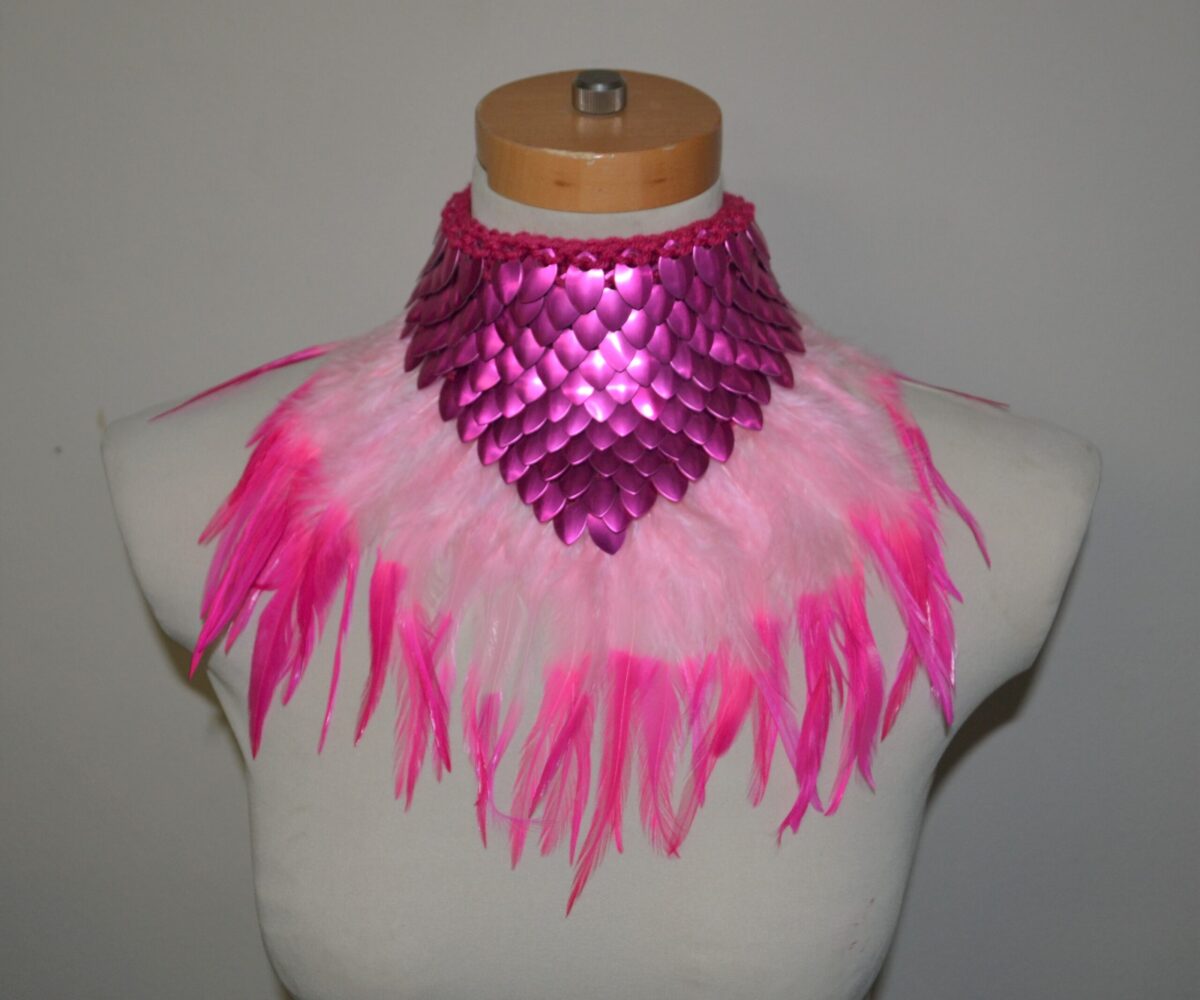 A pink dragonhide collar with feather trim in two colors of lighter pink, shown on a mannequin
