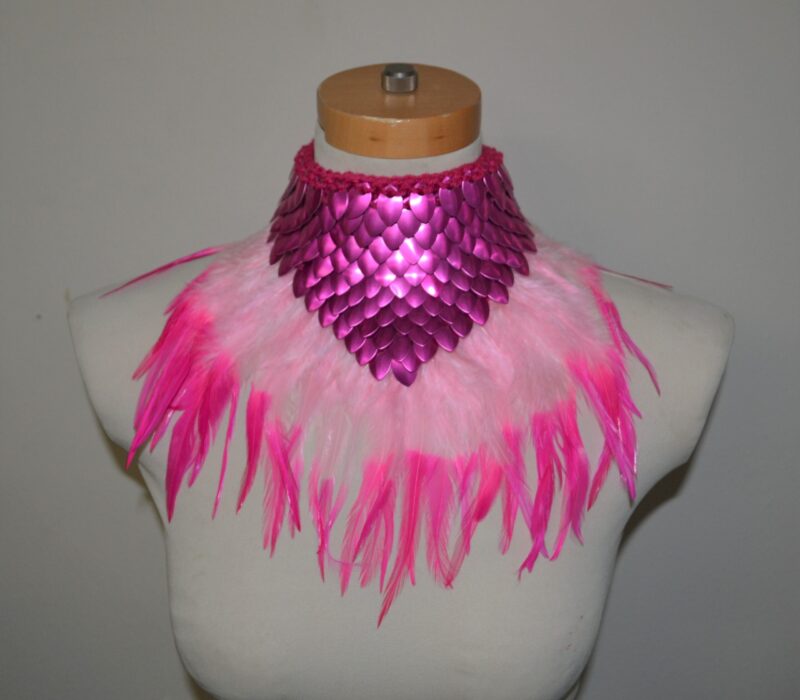 A pink dragonhide collar with feather trim in two colors of lighter pink, shown on a mannequin