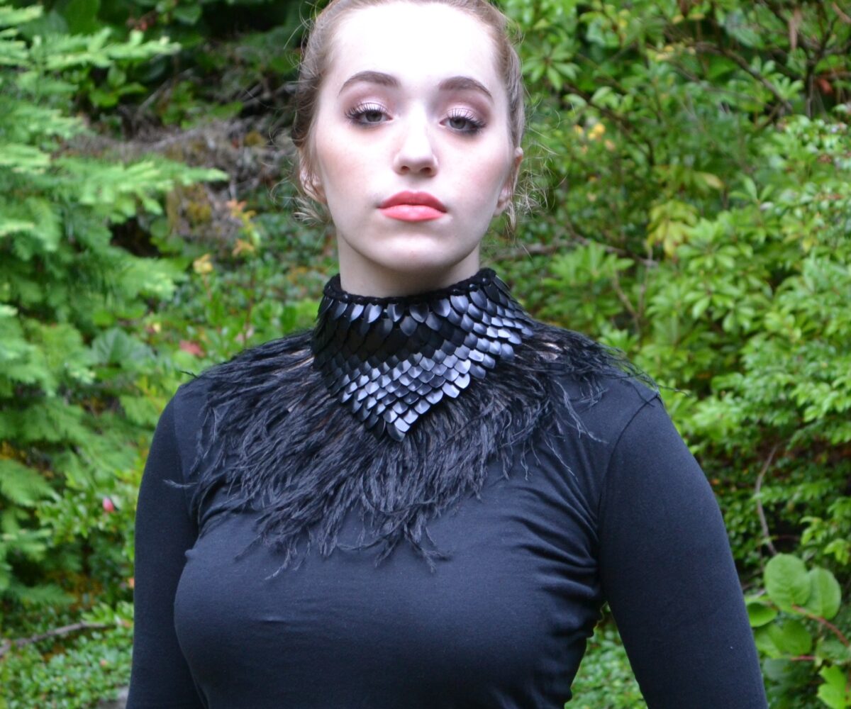 A black dragonhide colalr with feathery black trim, worn by a young woman