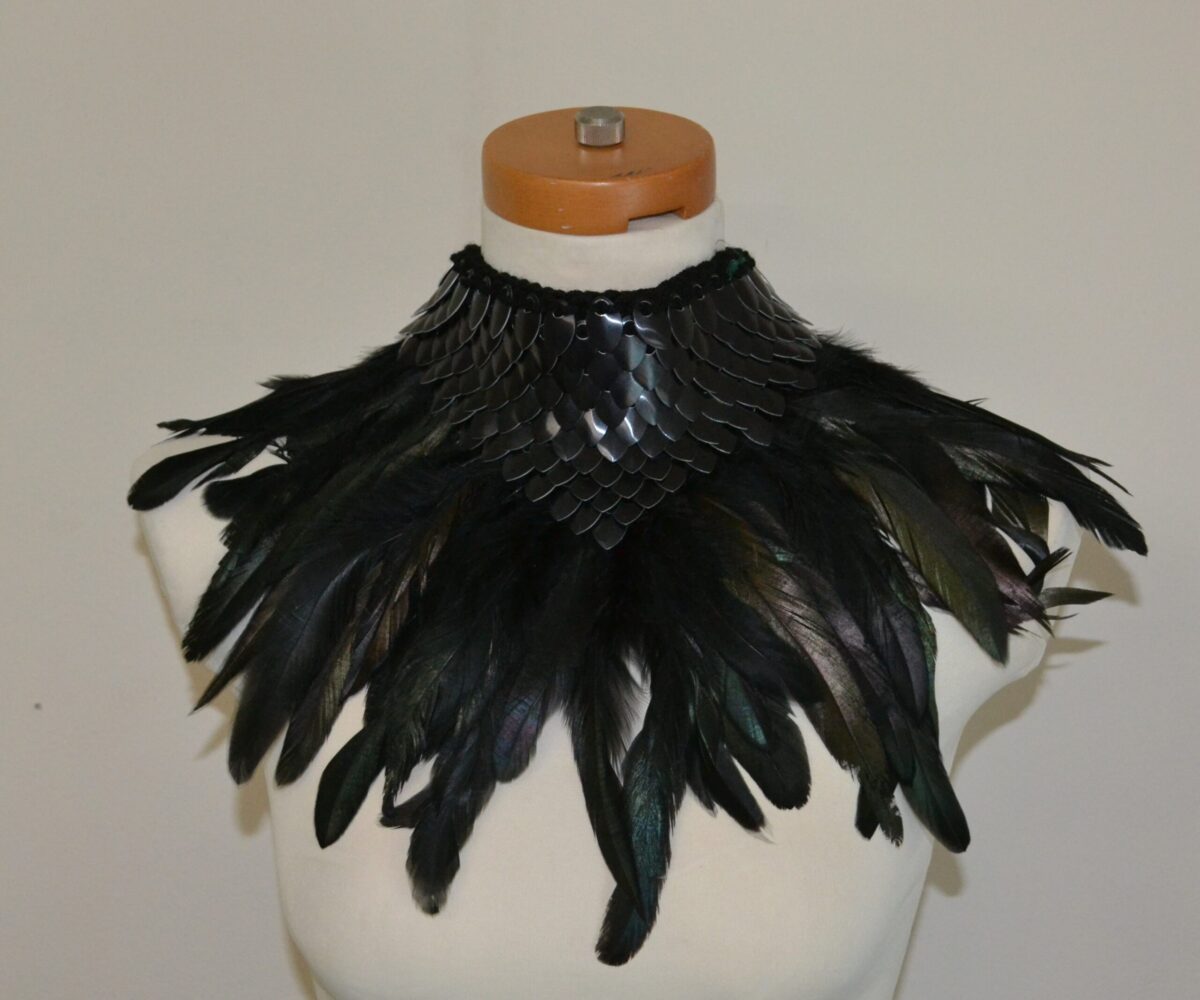A black knitted dragonhide collar with black feather trim, shown on a mannequin